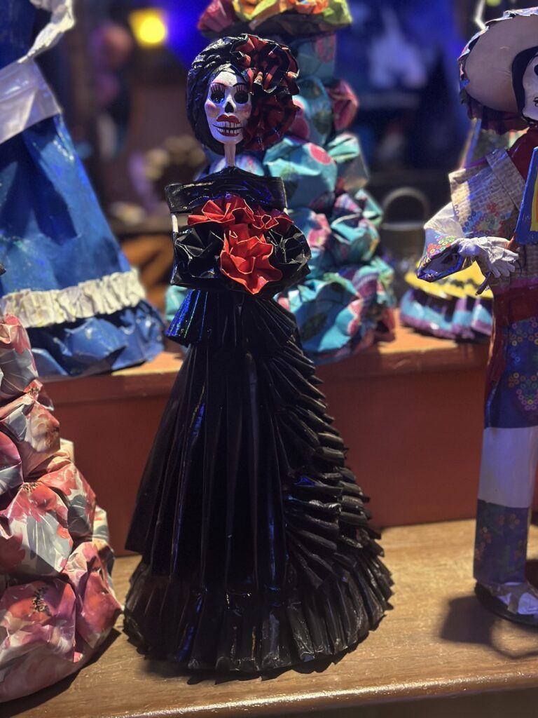 Dia de Muertos doll in a black dress with red flowers in the Mexico Pavilion in Epcot's World Showcase